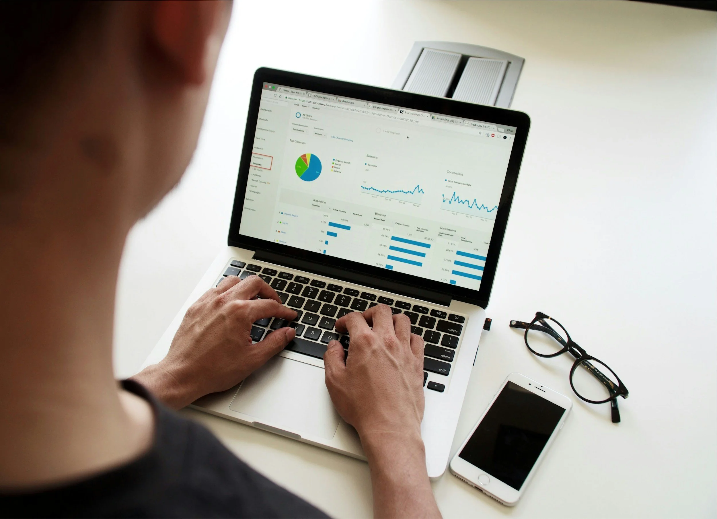 A person typing on a laptop displaying a graph, indicating data analysis or report preparation.