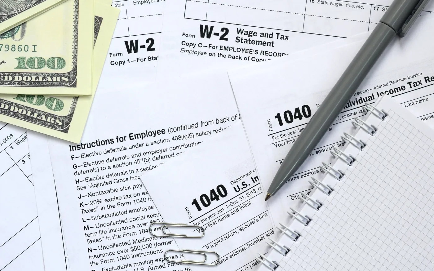 A calculator, tax forms, and stacks of coins representing financial calculations and tax preparation.
