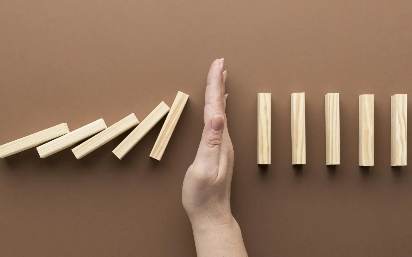 A person assembling wooden blocks in a line to create a domino effect.