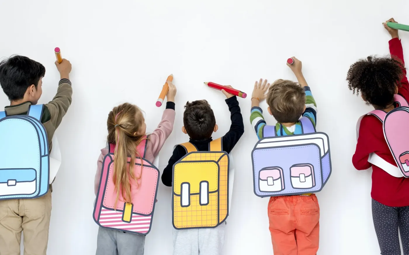 A group of children smiling and holding colorful backpacks, ready for school or an outdoor adventure.