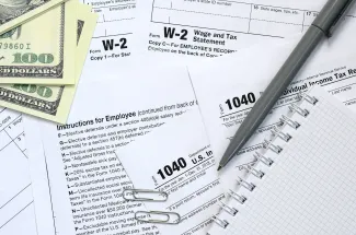 A calculator, tax forms, and stacks of coins representing financial calculations and tax preparation.