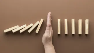 A person assembling wooden blocks in a line to create a domino effect.